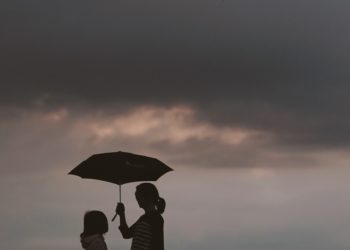 silhouette of woman holding umbrella standing in front of girl on hill during night time